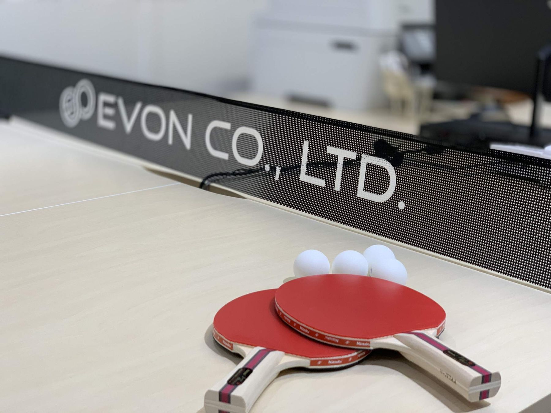 EVON CO., LTD. のロゴが入った卓球ネットと赤いラケット